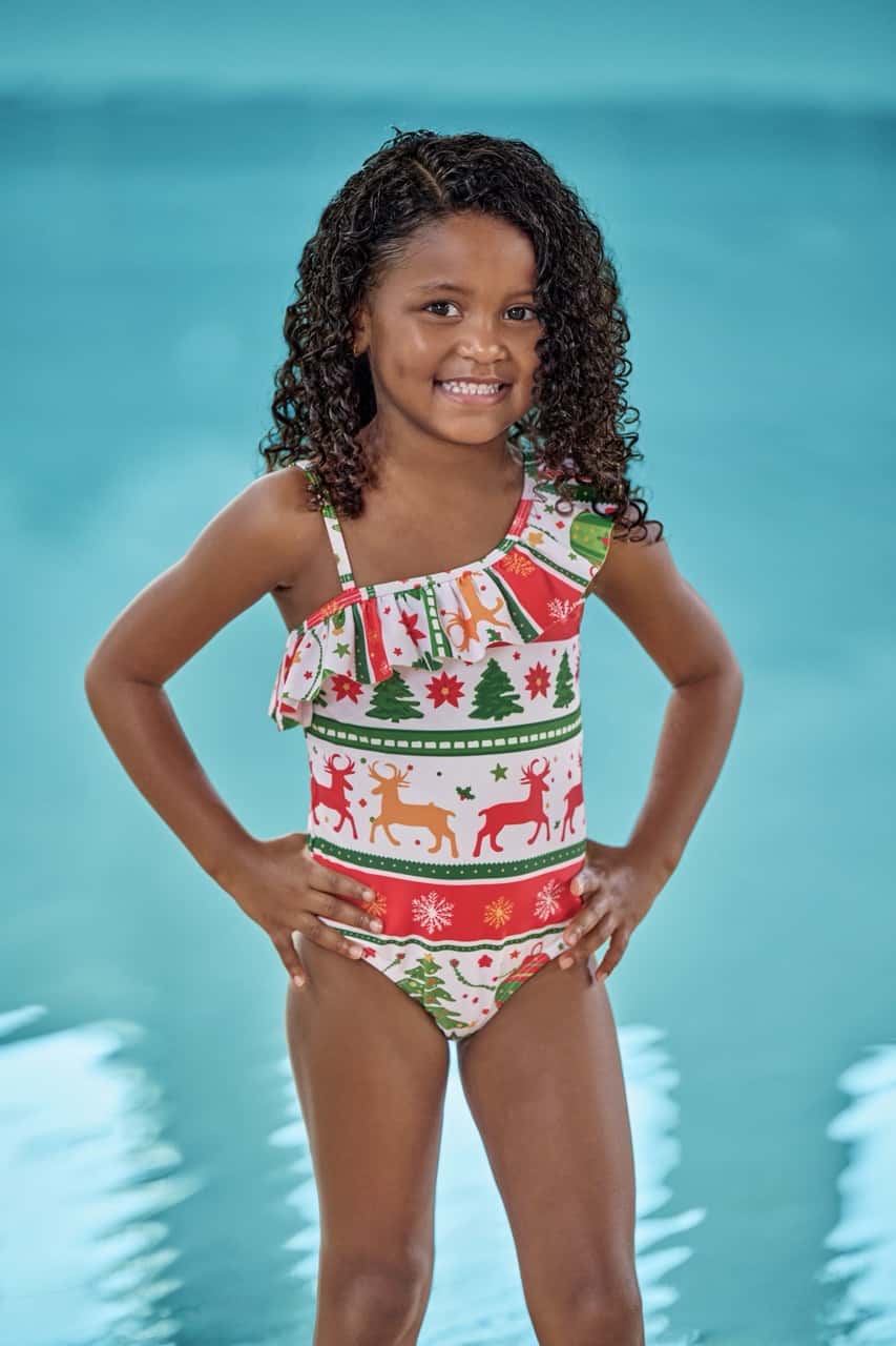 a girl wearing a holiday themed swimwear in white with green and red colors